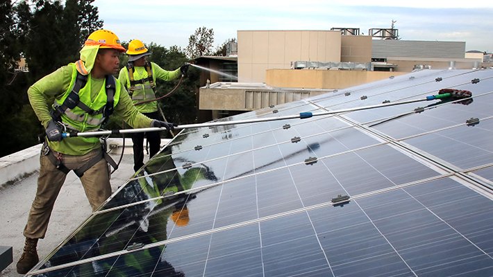 Photo of men cleaning solar panels.
