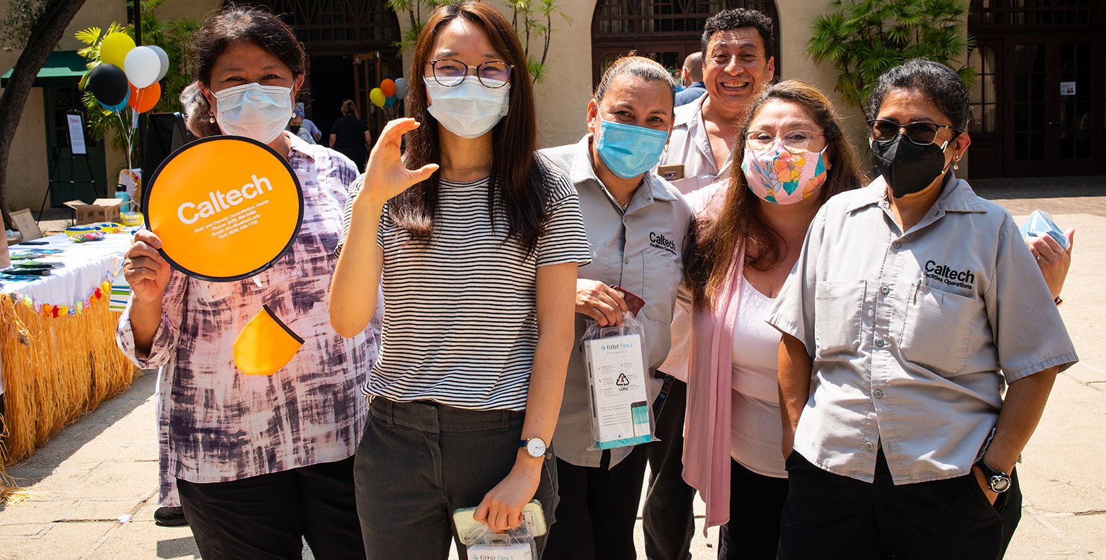 A group of people wearing masks smile at the camera
