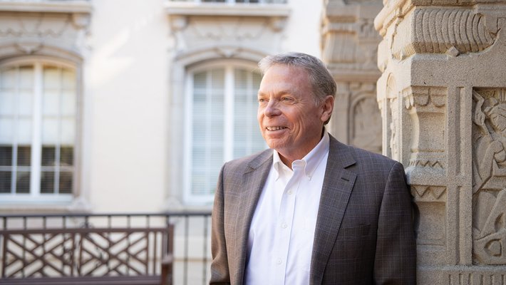 Provost David Tirrell in a white shirt and gray jacket, looking off to the left
