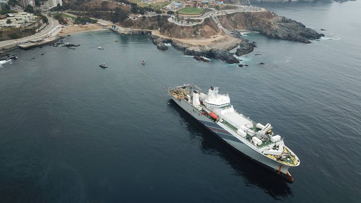 A ship, bottom right, steams out from shore unspooling the Curie cable