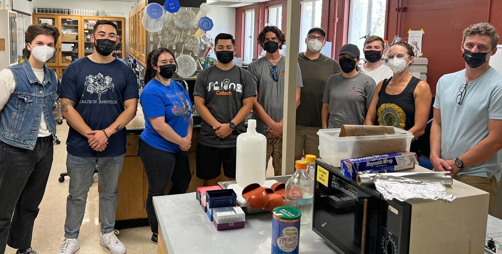 nine people wearing medical masks standing in a lab