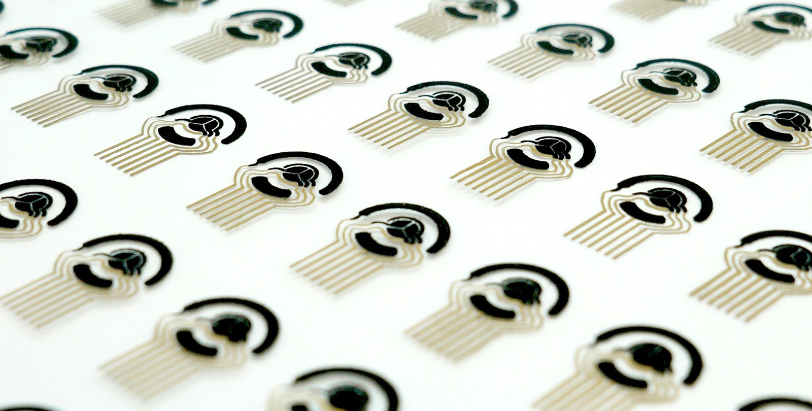 A sheet of printed out flexible sensor patch arrays. The sensors are black and gold and are on a white background.