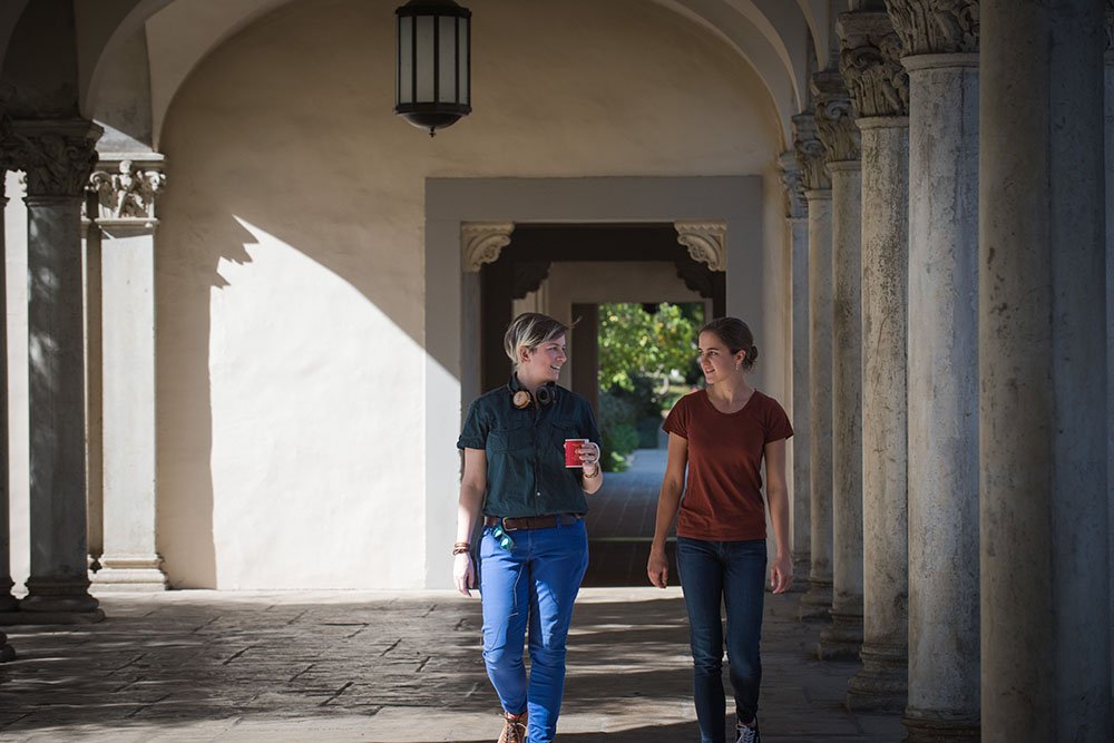 Fourth-year graduate student Giuliana Viglione (left) and her mentee, first-year Cora Went (right) walk through a hallway.