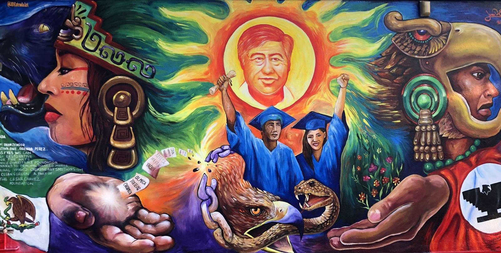 mural showing two graduates in blue gowns with diplomas with an eagle and a snake below them, with Aztec-influenced images, the Mexican flag, and a man with a red flag