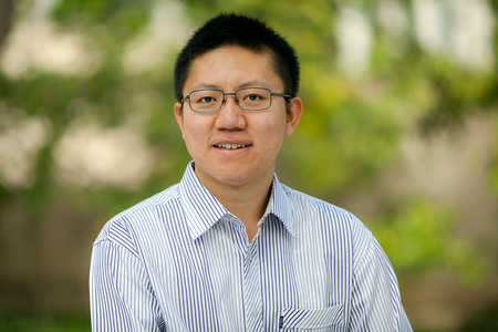 Portrait of Yimeng Li in a striped shirt with green out-of-focus background